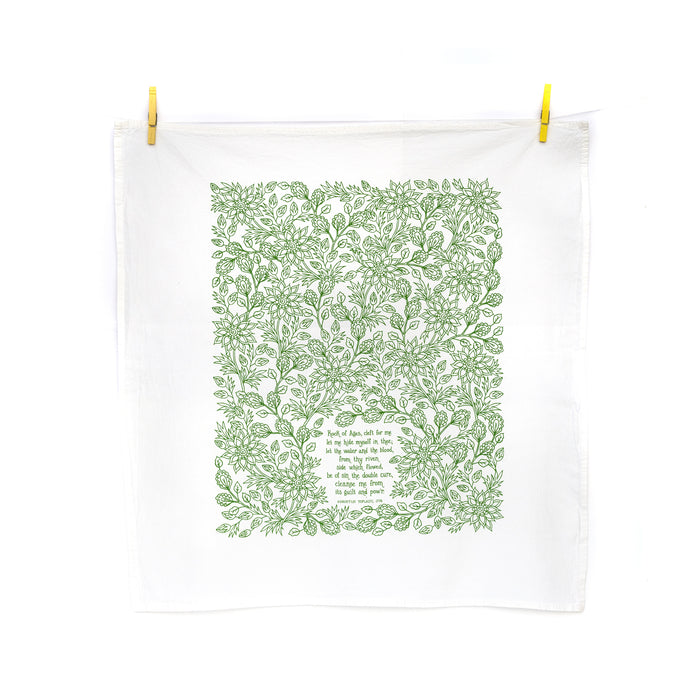 The redesigned "Rock of Ages" tea towel is printed in clover green and features floral illustrations and lyrics from the hymn. 100% cotton; US made. Shown here hanging from wooden clothes pins against a white background.