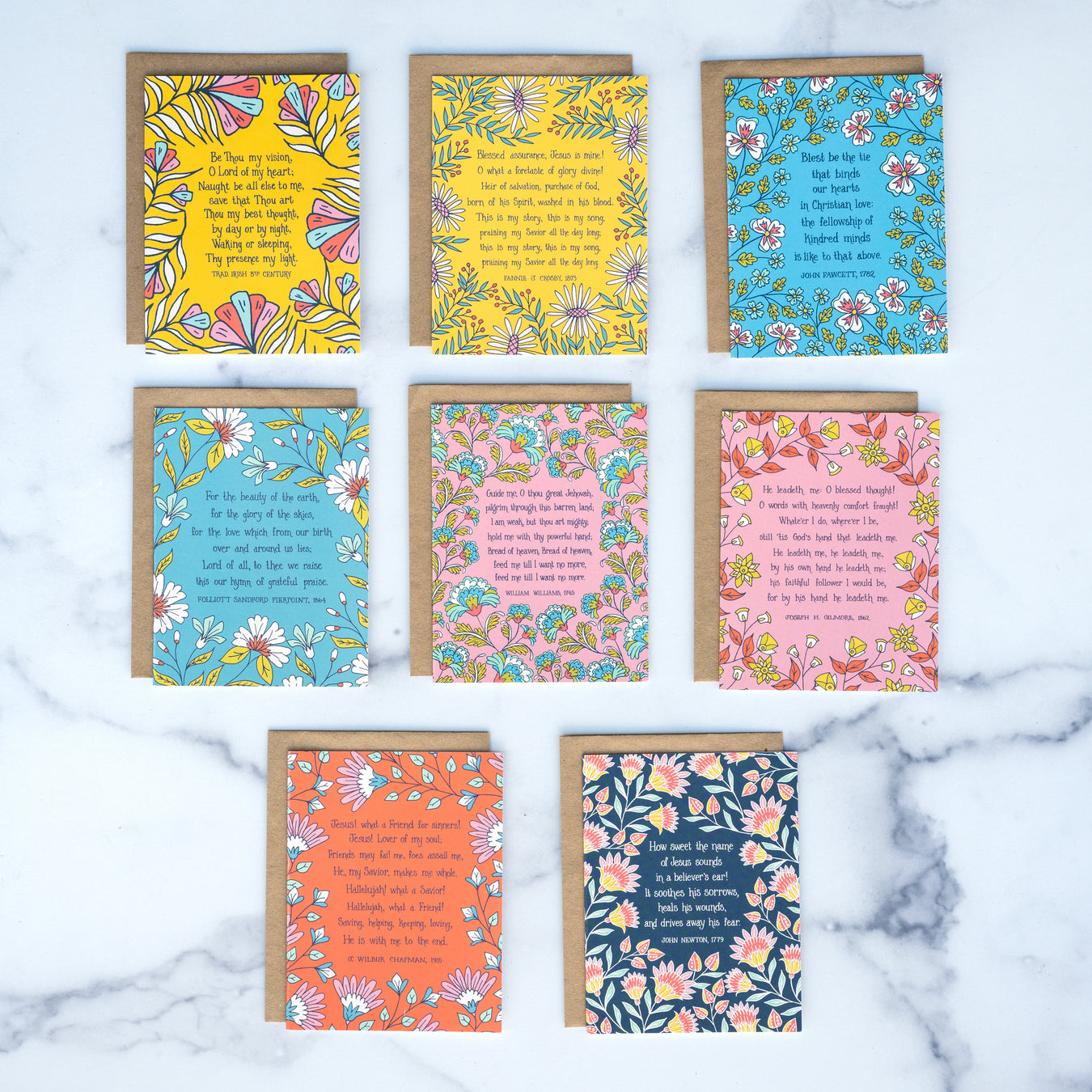 These 8 hymn greeting cards are the perfect way to say "I'm thinking of you" or "I care about you." Each card features a hymn's lyrics on the front and its history on the back. Shown as the set of 8 with kraft paper envelopes against a marble background.