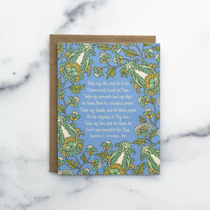 The Take My Life and Let It Be hymn greeting card, framed by saffron and moonstone floral against a stormy blue background, shown with a kraft paper envelope against a marble background.