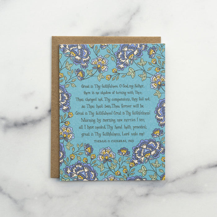 The Great Is Thy Faithfulness hymn greeting card, framed by thunder blue and moonstone floral against a turquoise background, shown with a recycled kraft paper envelope against a marble background.