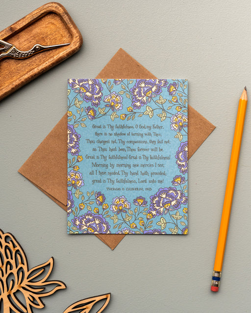 The Great Is Thy Faithfulness hymn greeting card, framed by thunder blue and moonstone floral against a turquoise background, is styled with a recycled kraft paper envelope, no.2 pencil, an antique envelope opener, and a wooden flower stem.