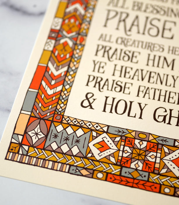 Doxology hymn art print — biblical wall art pictured as an 11x14 print showcasing a muted blue, red, and yellow stained glass border around dark hand-lettered text detail