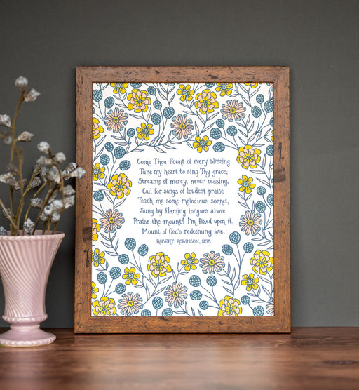 Come Thou Fount hymn wall art 11x14 delicate blue, yellow and pink floral surrounding a handwritten hymn styled with a vase and flowers in a brown wood frame