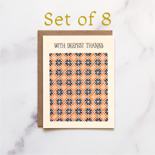 Our "With Deepest Thanks" Greeting Card is a hand illustrated geometric pattern highlighted with blues and corals on a pale yellow background, shown here against a marble background—a blank thank you card.