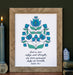 The "God Is Our Strength" Scripture art print features the hand-lettered verse Psalm 46:1 is accented by a blue and green floral motif against a cotton white background, shown in a wood frame styled with a candle, books, and a figurine.