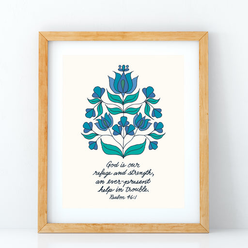 The "God Is Our Strength" Scripture art print features the hand-lettered verse Psalm 46:1 is accented by a blue and green floral motif against a cotton white background, shown in a wood frame against a white background.