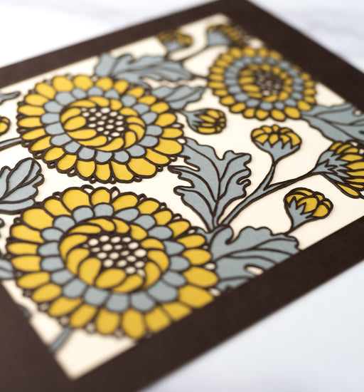 Detail image of the Layered Floral Papercut “Lou” (Fudge), which is made using cardstock in hues of hot fudge, steel blue, mustard, cream.