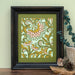 The Layered Floral Papercut “Margot” (Spearmint) is made using cardstock in hues of Jellybean green, salmon, mustard, spearmint, shown framed and styled with a vase eucalyptus, bird figurine and pinecone.