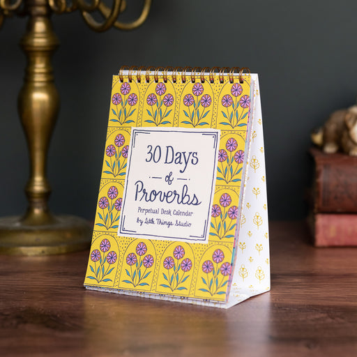 30 days of Proverbs - vibrant perpetual calendar on an easel, shown on a wooden desk, styled with a candelabra, stack of books and ceramic animals.