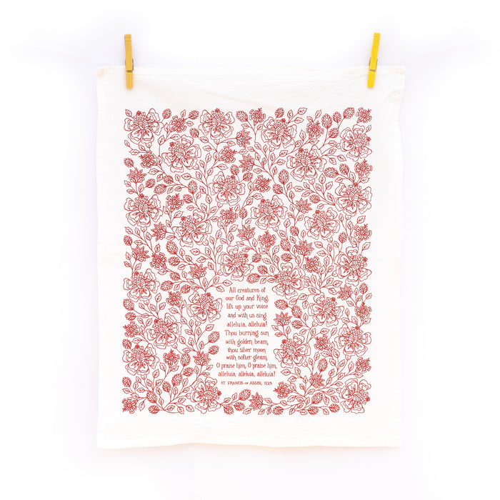 All Creatures of our God and King Scripture tea towel is printed in rich crimson, displayed folded against a white marble background