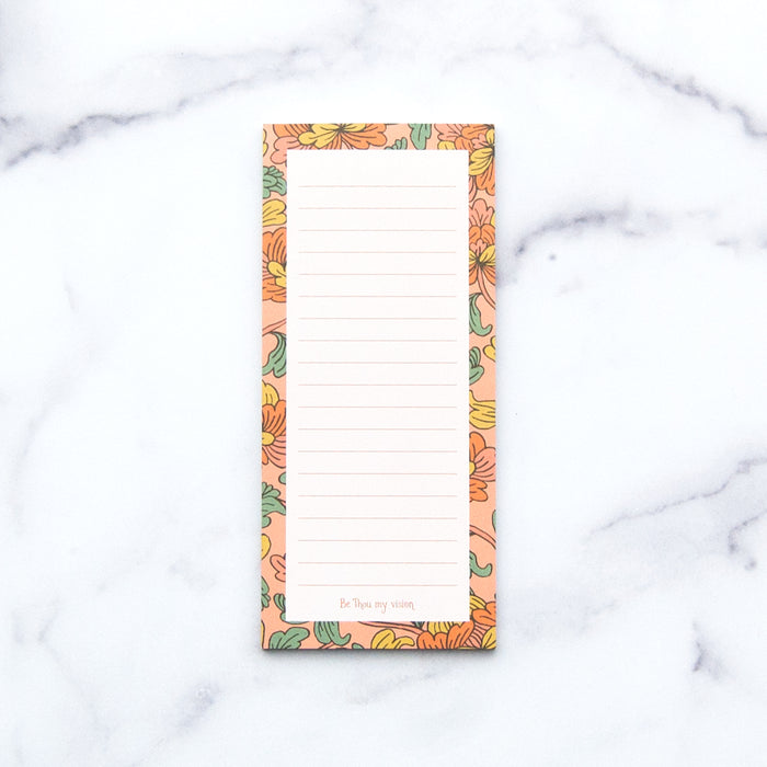 The "Be Thou My Vision" notepad features a hand illustrated floral border, "Be Thou my vision" at the bottom, and a magnet on back, shown against a white marble background.