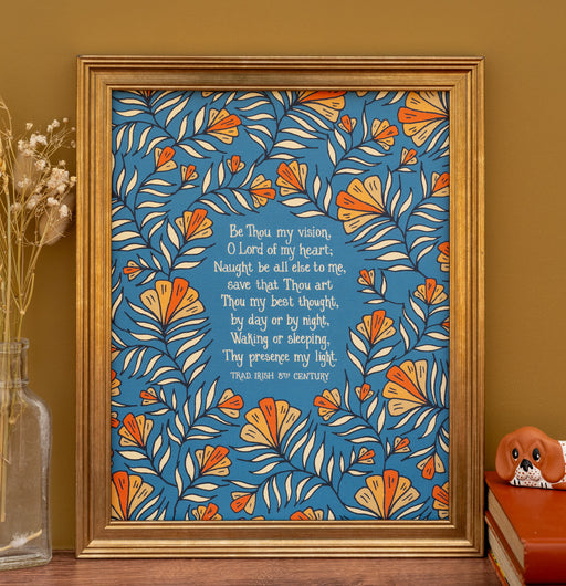 This "Be Thou My Vision" hymn art print features the much loved hymn text surrounded by a unique peach floral against a teal background; shown here in a gold frame against a khaki colored background, and styled with a vase of dried grasses and a ceramic figurine.