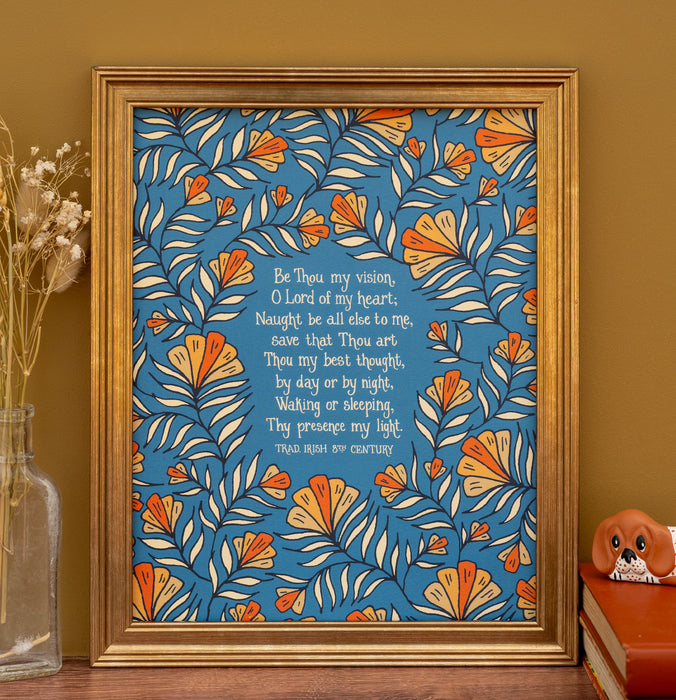 This "Be Thou My Vision" hymn art print features the much loved hymn text surrounded by a unique peach floral against a teal background; shown here in a gold frame against a khaki colored background, and styled with a vase of dried grasses and a ceramic figurine.