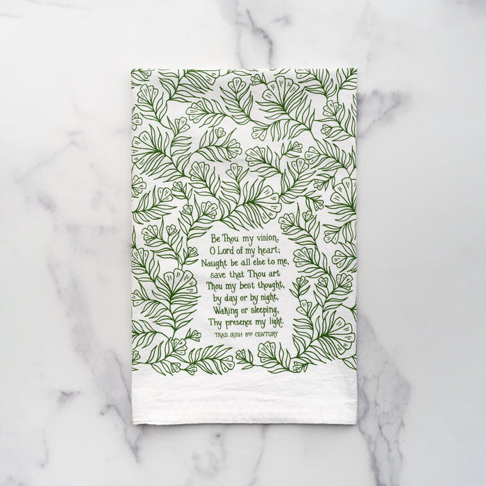 The Be Thou My Vision hymn tea towel is printed in forest green and features lyrics from the hymn, shown folded against a marble backdrop.