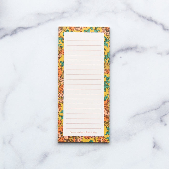 Little Things Studio's beautiful "Blessed Assurance" notepad features a hand illustrated floral border with "Blessed assurance, Jesus is mine!" at the bottom. Pictured against a white marble background.