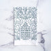 The Blessing Scripture tea towel is printed in muted blue-green tone and features the verse from Numbers 6:24–26. Made of 100% cotton. Shown here folded against a marble background.