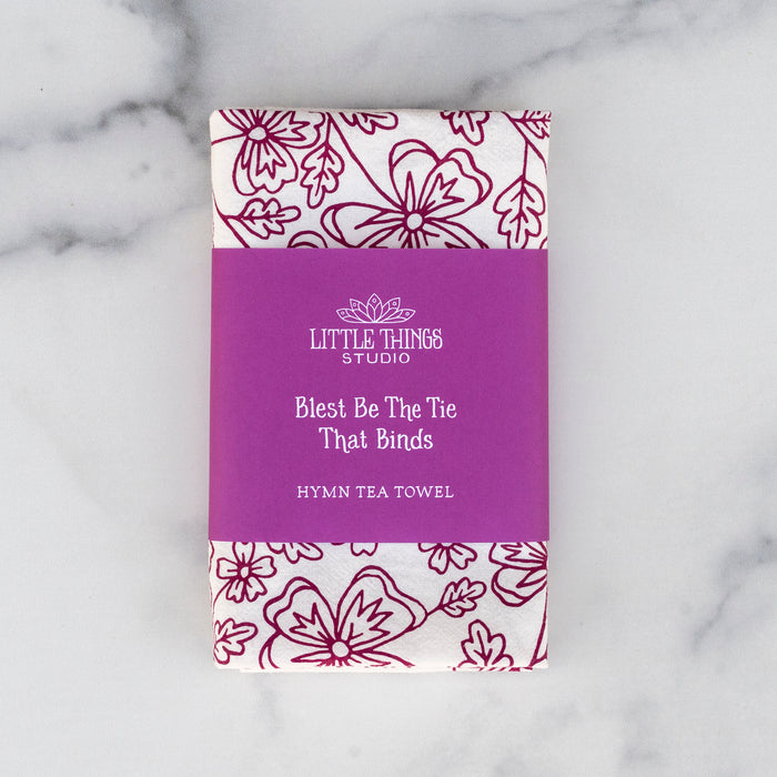 Blest Be the Tie hymn tea towel, printed on a cotton flour sack in midnight magenta, displayed folded with a paper belly band for gift giving