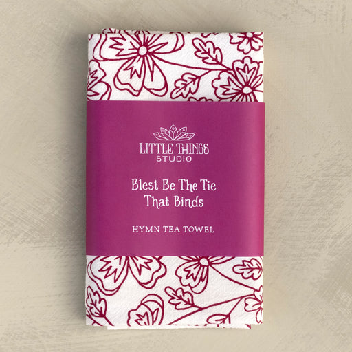 Blest Be the Tie hymn tea towel, printed on a cotton flour sack in midnight magenta, displayed folded with a paper belly band for gift giving