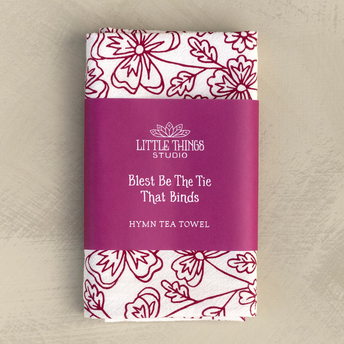 Blest Be the Tie hymn tea towel, printed on a cotton flour sack in midnight magenta, displayed folded with a paper belly band for gift giving