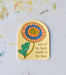 The "Blessed Assurance" hymn sticker features an arched window silhouette, colorful floral and lyrics, "born of his Spirit, washed in His blood." Shown against a worktable background.