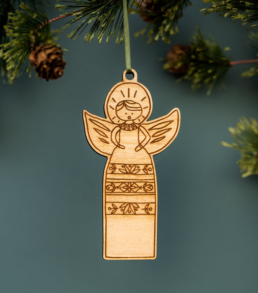 All-new Christmas ornaments from Little Things Studio featuring this sweet caroling angels with floral motif dresses, adding a touch of whimsy and cheer to your holiday decor. Laser cut in-house from bright maple plywood, threaded with a ribbon and ready for your tree! Shown hanging from a Christmas tree.