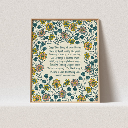 This "Come Thou Fount" hymn art print features the beloved hymn text surrounded by a lively floral and will brighten up any room. Shown in a light wood frame against a white background.