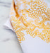 Little Things Studio presents floral tea towels featuring our unique illustrations in colorful hues. The Cordelia floral tea towel displays intricate florals in a cheerful daffodil, displayed here folded against a marble backdrop.