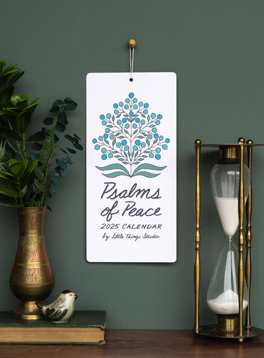 Celebrate 2025 with treasured verses from the Book of Psalms, accented by unique floral patterns and new script-style hand-lettering, shown here styled with greens in a bronze vase alongside an hour-glass.