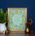 The "Dear Refuge Of My Weary Soul" hymn art print, surrounded by a gorgeous blue and lavender floral with a light teal background, is displayed in a gold frame alongside a vase of fresh greens and various figurines, against a navy blue wall.