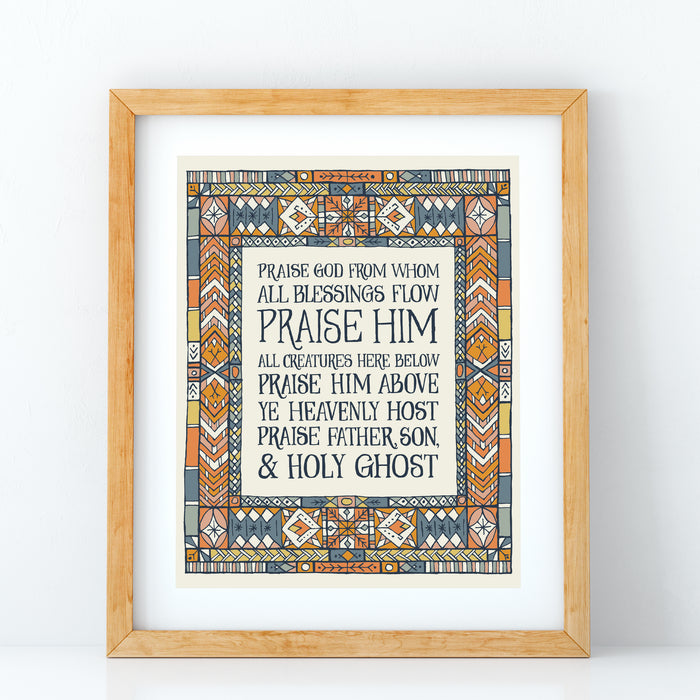 Doxology hymn art print — biblical wall art showcasing the soft blue, peach, and gold stained glass border that surrounds the hand-lettered text, framed in a light wood frame against a white background.