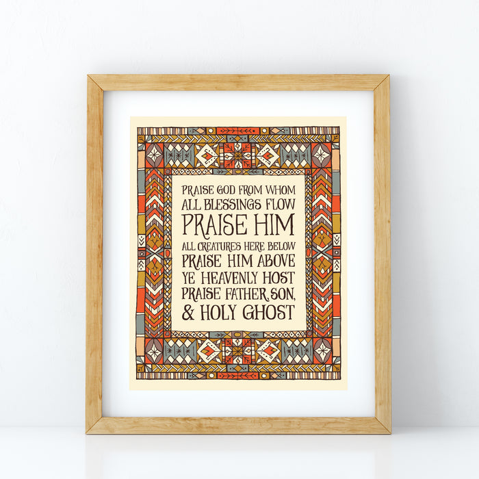 Doxology wall art featuring hand lettered text surrounded by a multi-coloured stained glass illustration, displayed in a light wood frame