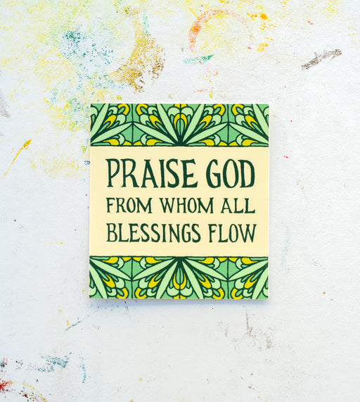 The "Doxology" hymn sticker features the opening line of the Doxology in hand lettered text against a cream background with a mint green floral motif. Shown here against a white worktable background.