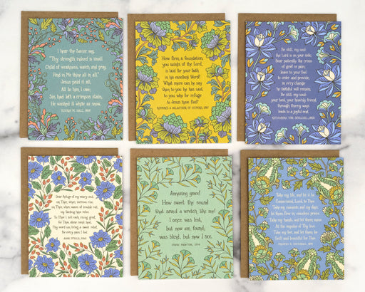 Each of the 6 hymn greeting cards in set "Frances" features a hymn's lyrics on the front and its history on the back, shown here flat with recycled kraft paper envelopes against a marble background.