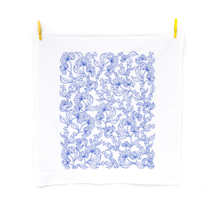 Little Things Studio presents floral tea towels featuring our unique illustrations in colorful hues. The Francine floral tea towel displays airy floral design of flowers and buds in a bright bluebell, displayed here unfolded and hanging with clothes pins.