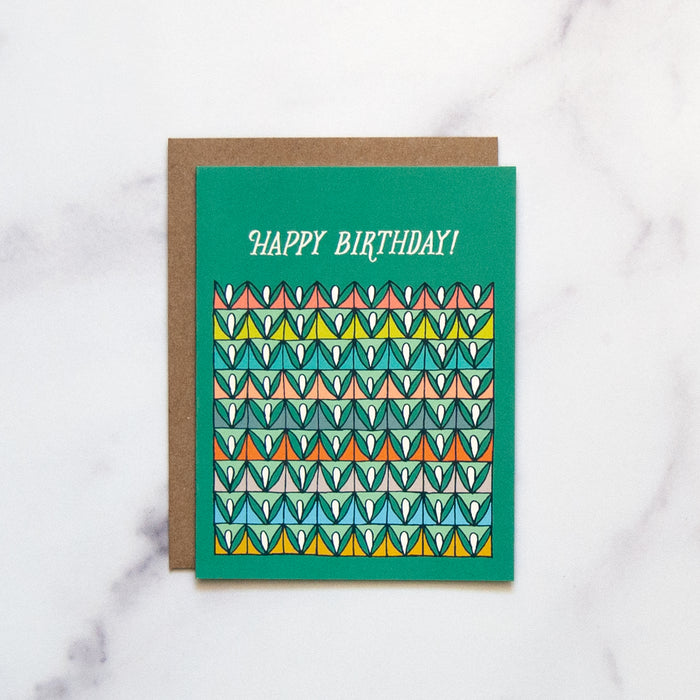 The Happy Birthday! card is a blank birthday card with cheerful, vibrant illustrations against a happy green background, shown here against a white marble backdrop.