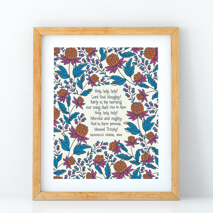 Holy Holy Holy art print — biblical wall art featuring hand lettered text surrounded by floral illustrations in shades of magenta, teal, and burnt orange displayed in a wood frame against a white background.