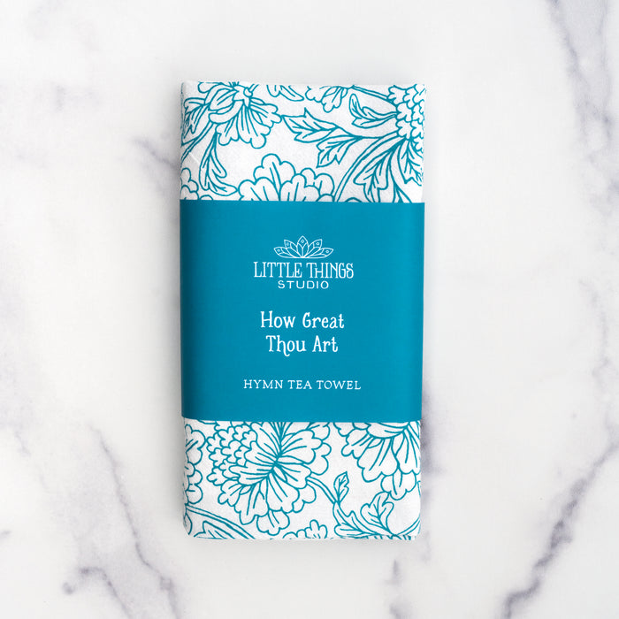 How great thou art tea towel in aqua blue folded and wrapped with a paper belly band