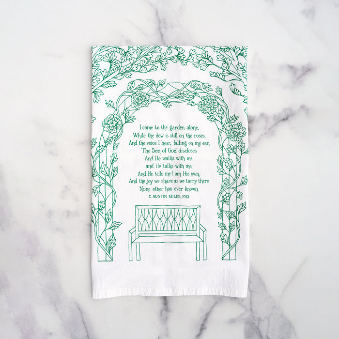 The much loved gospel song "In The Garden" is printed in a stunning paradise green on 100% cotton tea towel, shown here folded against a marble backdrop.