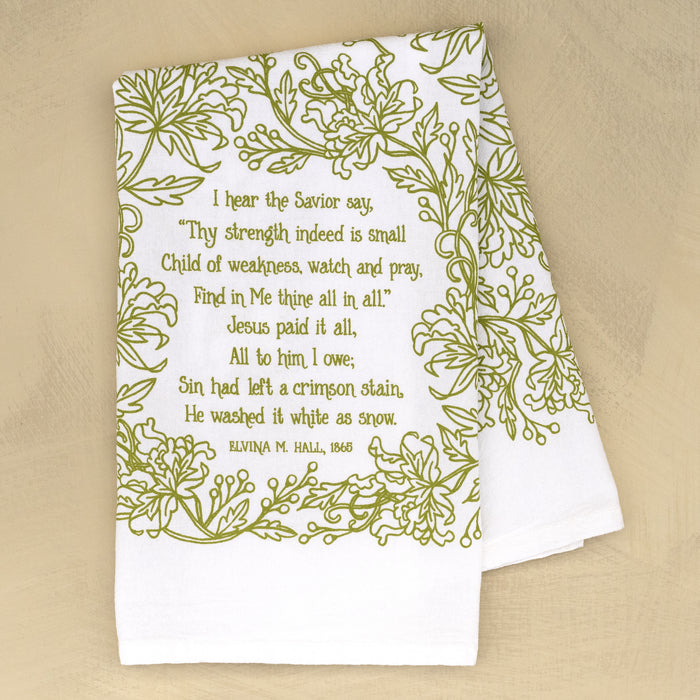 Jesus Paid It All hymn tea towel printed in fresh springtime green, folded and set against a khaki background