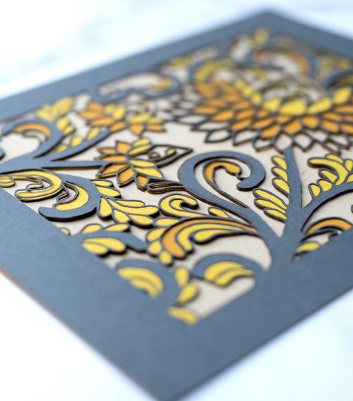 Detail image of the Layered Floral Papercut “Margot” (Dark Gray) is made using cardstock in hues of dark gray, pumpkin pie, mustard, and kraft.