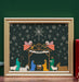 The Nativity Christmas art print features a vibrantly illustrated nativity scene surrounded by a striking night sky full of stars; shown in a gold frame accented by a candle