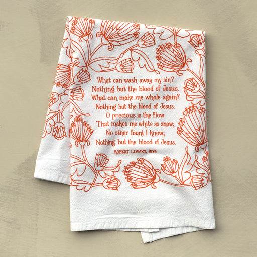 The Nothing But the Blood hymn tea towel is printed in sunset orange and features lyrics from the hymn accented by intricate floral illustration, shown folded against a khaki background