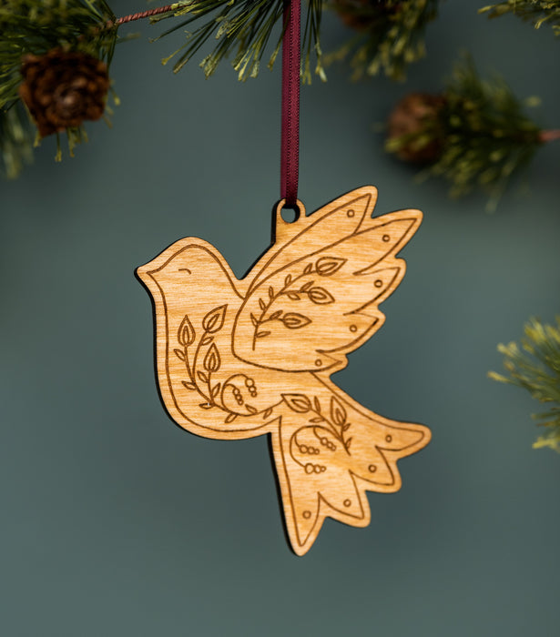 These exquisitely-engraved doves etched with beautiful foliage are one of the all-new Christmas hymn ornaments from Little Things Studio, shown threaded with ribbon and hanging from a Christmas tree.