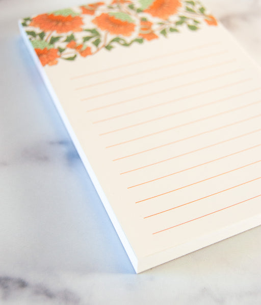 Detail of small coral colored floral notepad with lines for writing