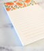 Detail of small coral colored floral notepad with lines for writing