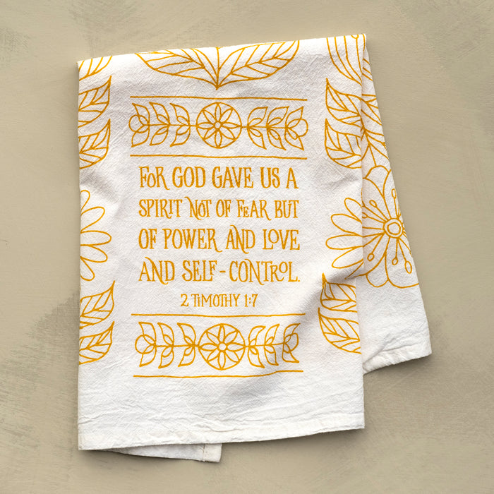 The Power, Love & Self-Control Scripture tea towel is printed in sunflower yellow and features 2 Timothy 1:7; shown folded against a khaki background.