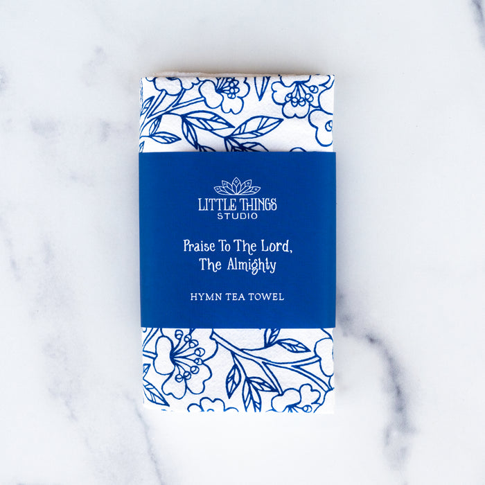 Praise to the Lord the Almighty hymn tea towel is printed in cobalt, displayed folded with a printed belly band for gift giving