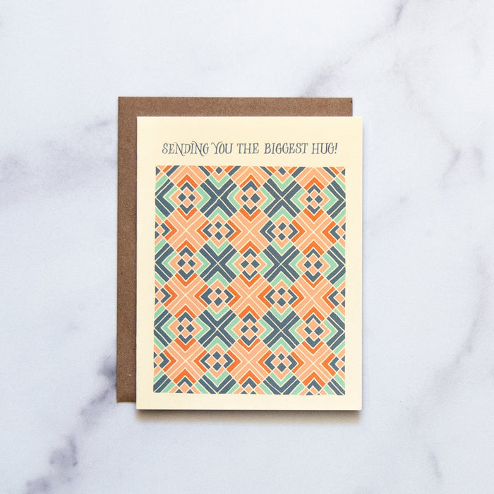 The Biggest Hug Greeting Card features a hand illustrated geometric pattern in blues and corals— a beautiful greeting card pictured against a white marble background.