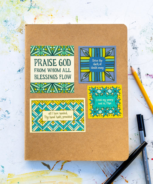 This set of four hymn stickers comes ready for you to place anywhere you need a reminder of what is good and true. Shown on a notebook, styled with pen and pencil against a worktable background.