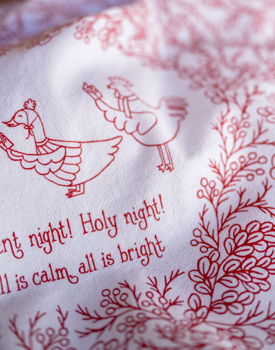 Illustration detail of Our Silent Night Christmas hymn tea towel, which features a hand-illustrated floral border and hand-lettered text, printed in holly berry red on a 100% cotton tea towel.